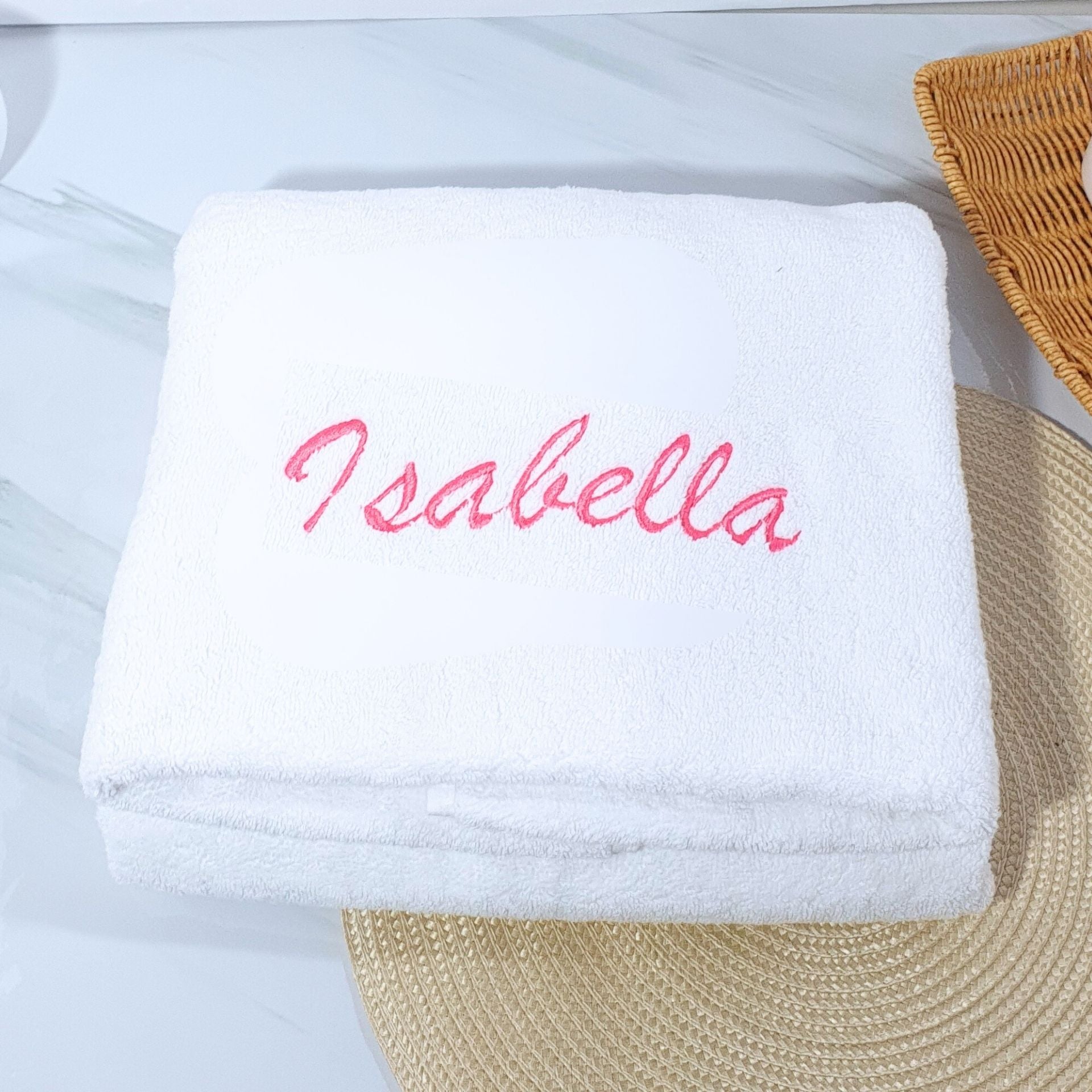 White bath towel with 'Isabella' embroidered in pink on a light blue background