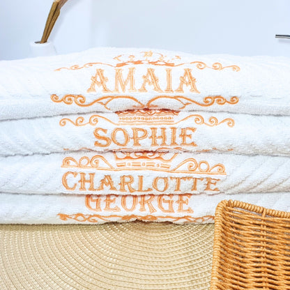 Stack of white towels with embroidered names on a light background