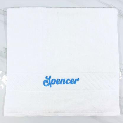 White hand towel with 'Spencer' embroidered in blue on a white background