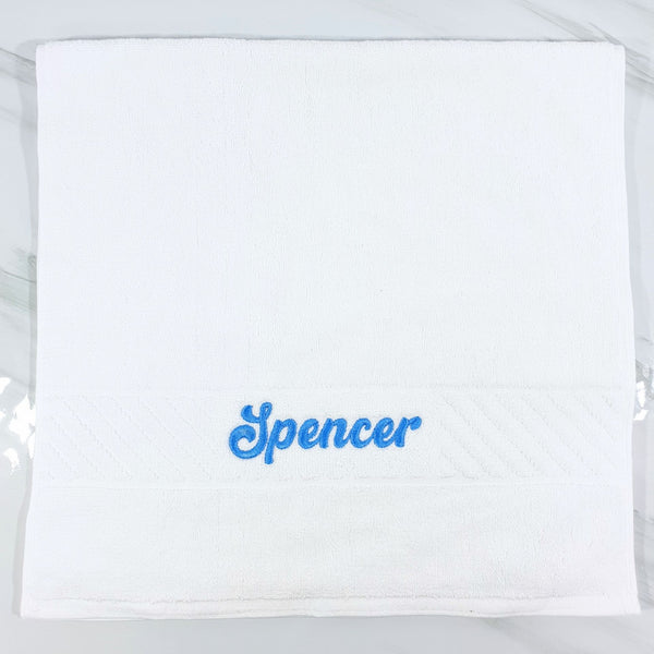White hand towel with 'Spencer' embroidered in blue on a white background