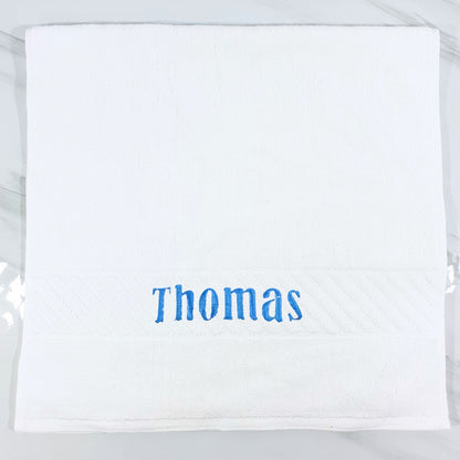 White hand towel with 'Thomas' embroidered in blue on a white background