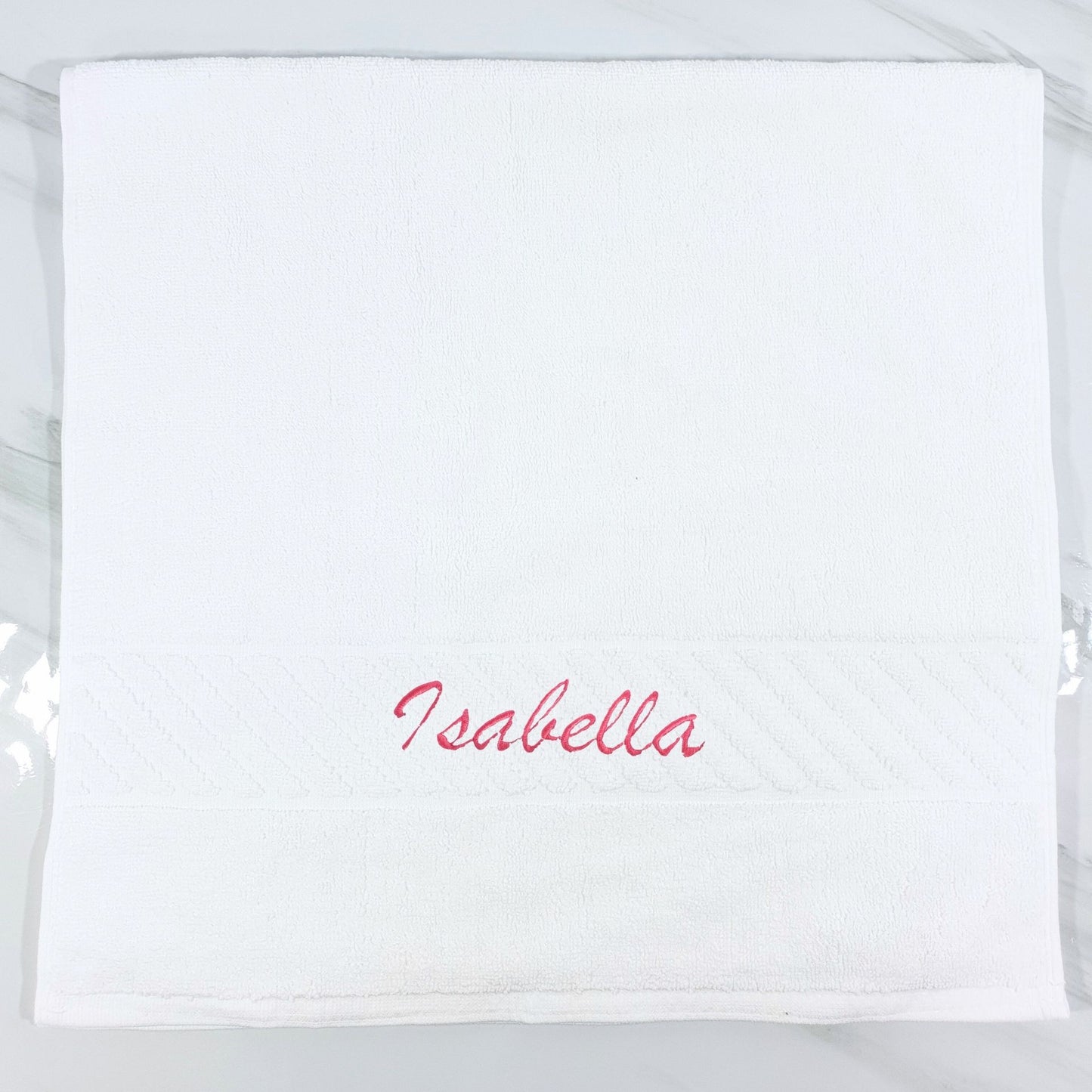 White hand towel with 'Isabella' embroidered in red on a white background